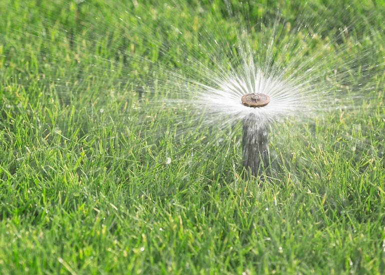 Automated watering system in action, set up in a well-maintained lush green lawn.